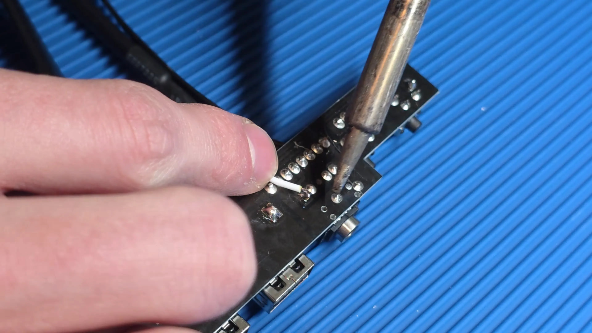 A screenshot of a video by Adam Lee/mryeester, showing the modification of a PC case front panel board, to use the audio jack as a power button