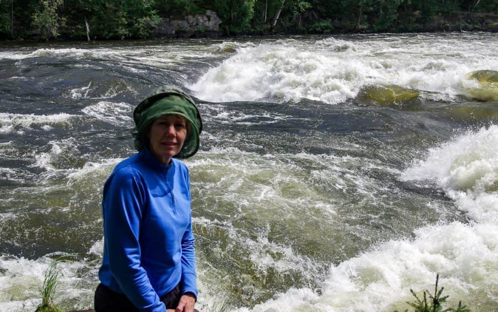 Decked out in a head net for the portage with Sluice Falls on the Churchill River in the background