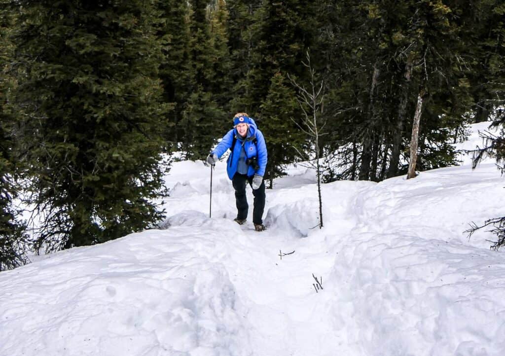 Woman climbing a steep snowy trail to Gypsum Mine Road in Kananaskis