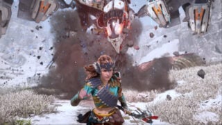 A screenshot from the Horizon Zero Dawn Remastered trailer, with Aloy trying to escape a large robot chasing after her. She clutches her bow in one hand, whilst the robot is sending debris flying everywhere.