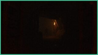 The dark caves in Those Who Dwell. There is a figure ahead standing by a torch.