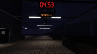 Screenshot from Darkest Hours showing a view across a dark paved courtyard with a brick floor and walls topped with iron fences. It is night time and the area is lit by bar lights attached to the fencing overhead.