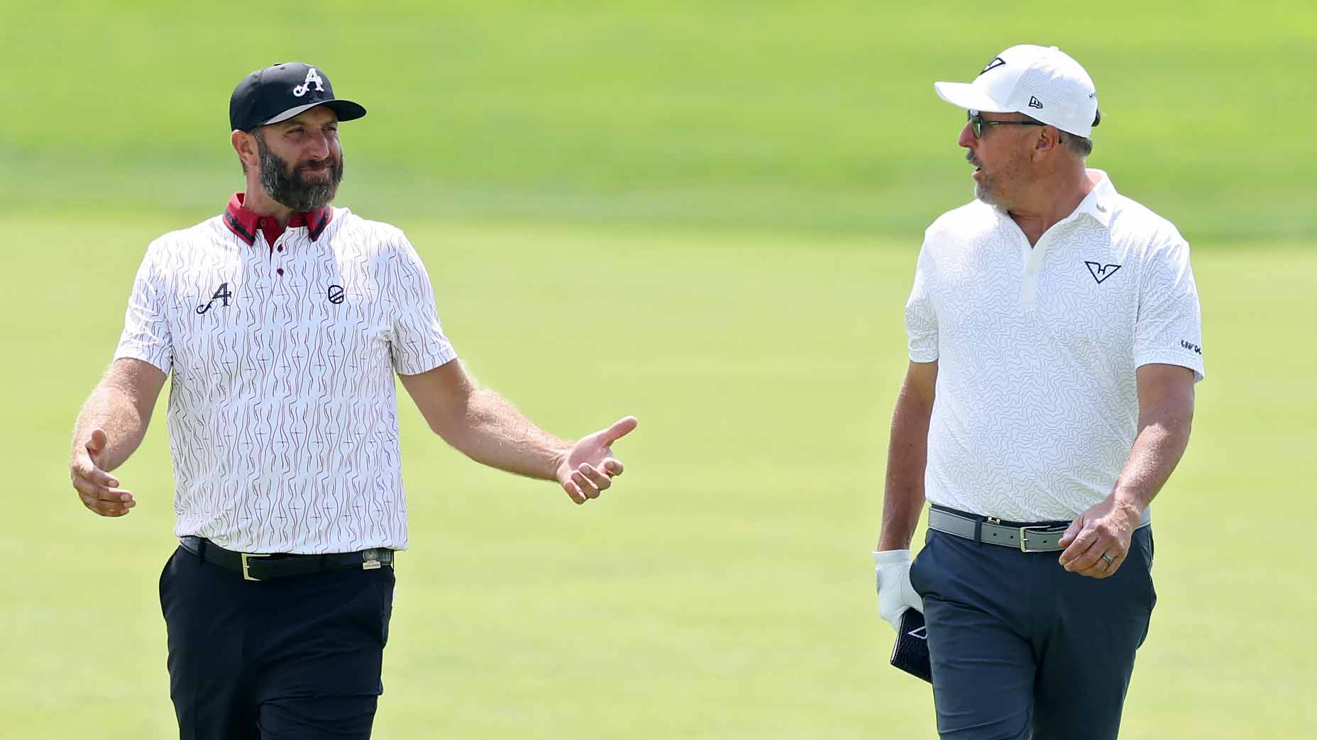 Dustin Johnson and Phil Mickelson walk side by side on a golf course at 2025 U.S. Open.