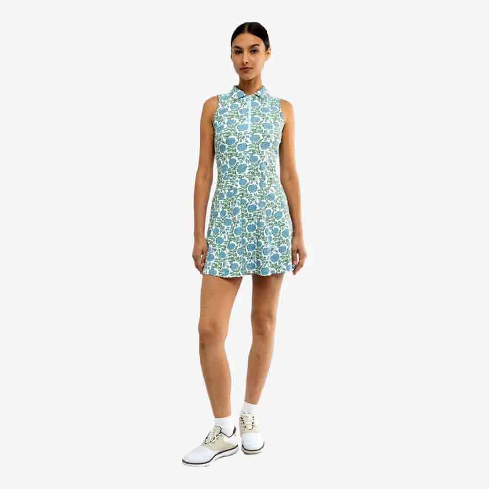 A woman stands against a plain background wearing a sleeveless, blue and green floral-patterned dress and white athletic shoes with ankle socks&mdash;an effortless, fresh look perfect for celebrating Mother&rsquo;s Day.