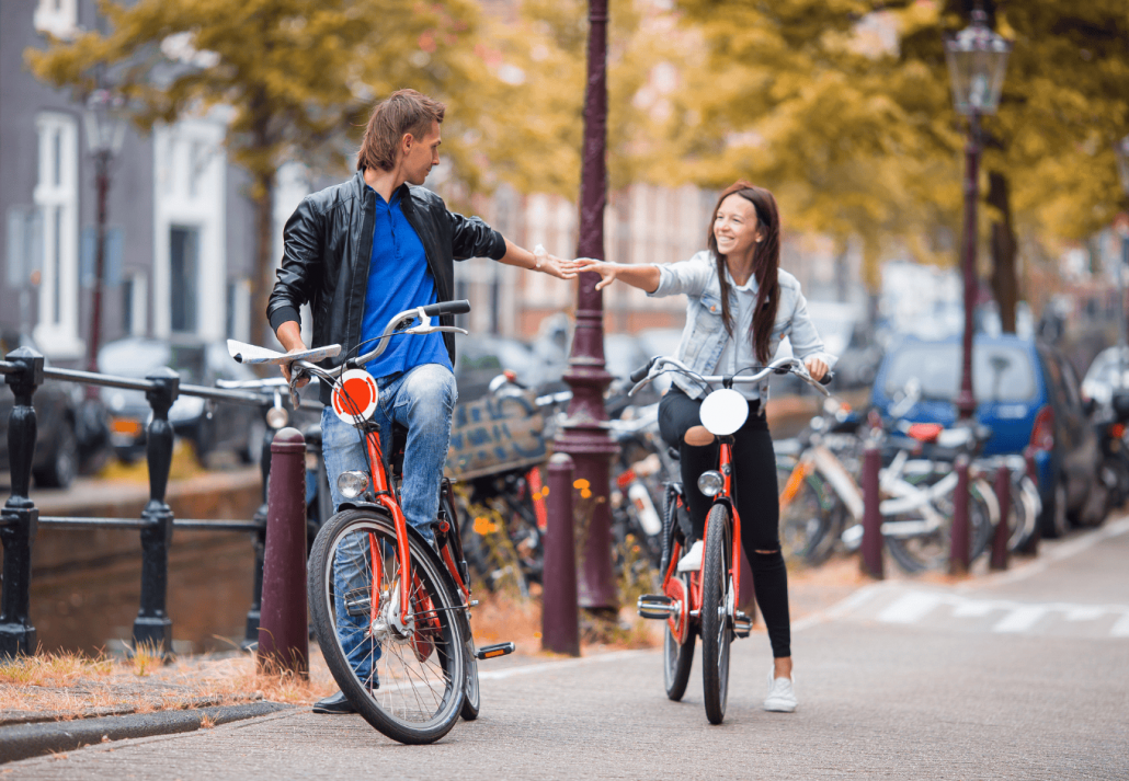 Young happy caucasian couple on bikes in old streets in Amsterdam