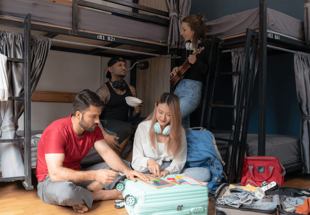 Groups of travelers of different nationalities having fun in the hostel.