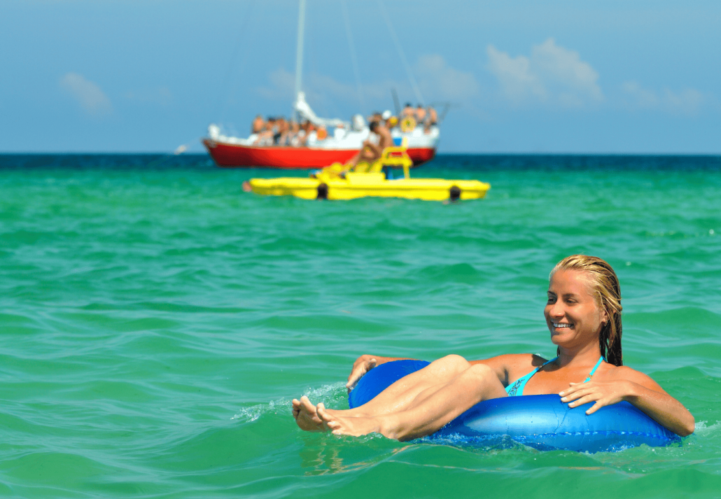 Young blond woman in blue bikini riding on swimming circle in sea and smiling