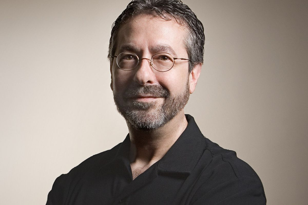 Warren Spector smiles at the camera.