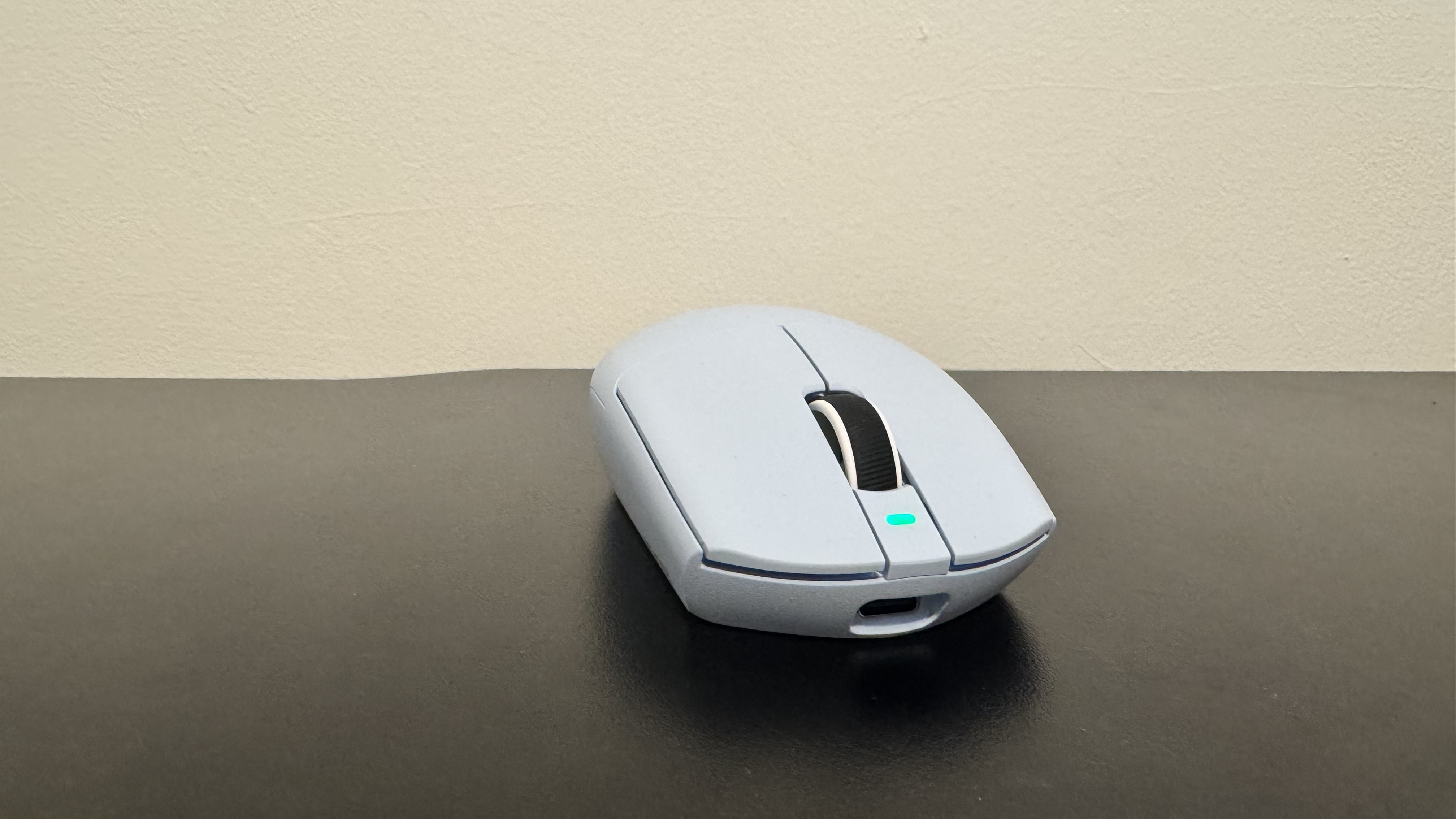 The blue Mchose G3 V2 gaming mouse from the front on a black desk