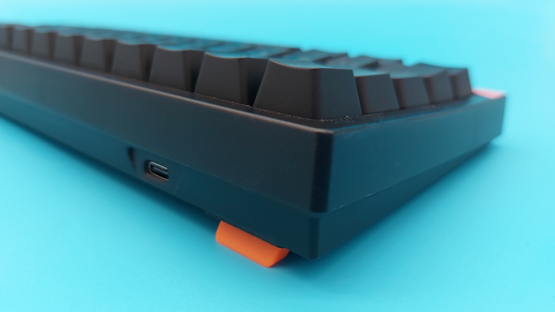 The Cherry K5 Pro TMR Compact seen from the back, with the orange feet flipped out to prop up the gaming keyboard.