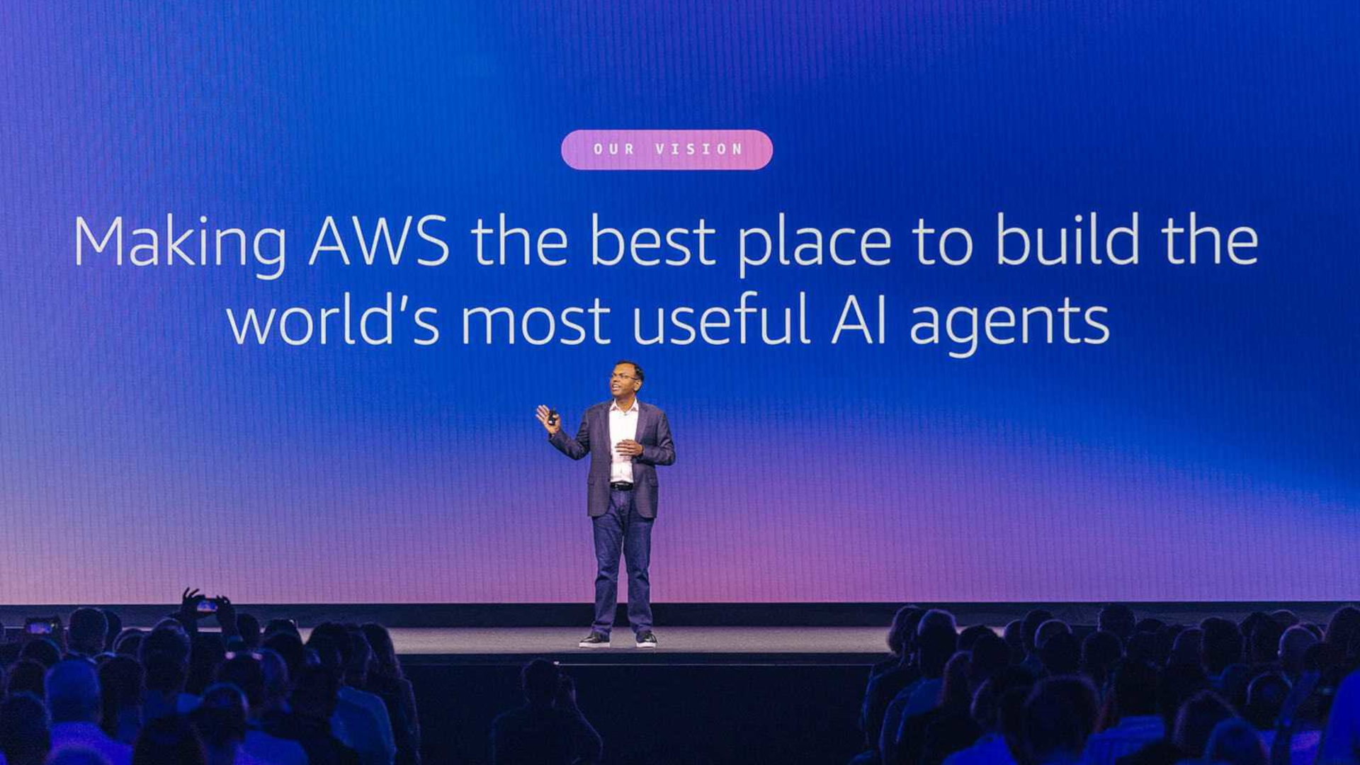 A photo of Swami Sivasubramanian, Amazon's VP of Agentic AI, standing on a stage with a background behind him stating 