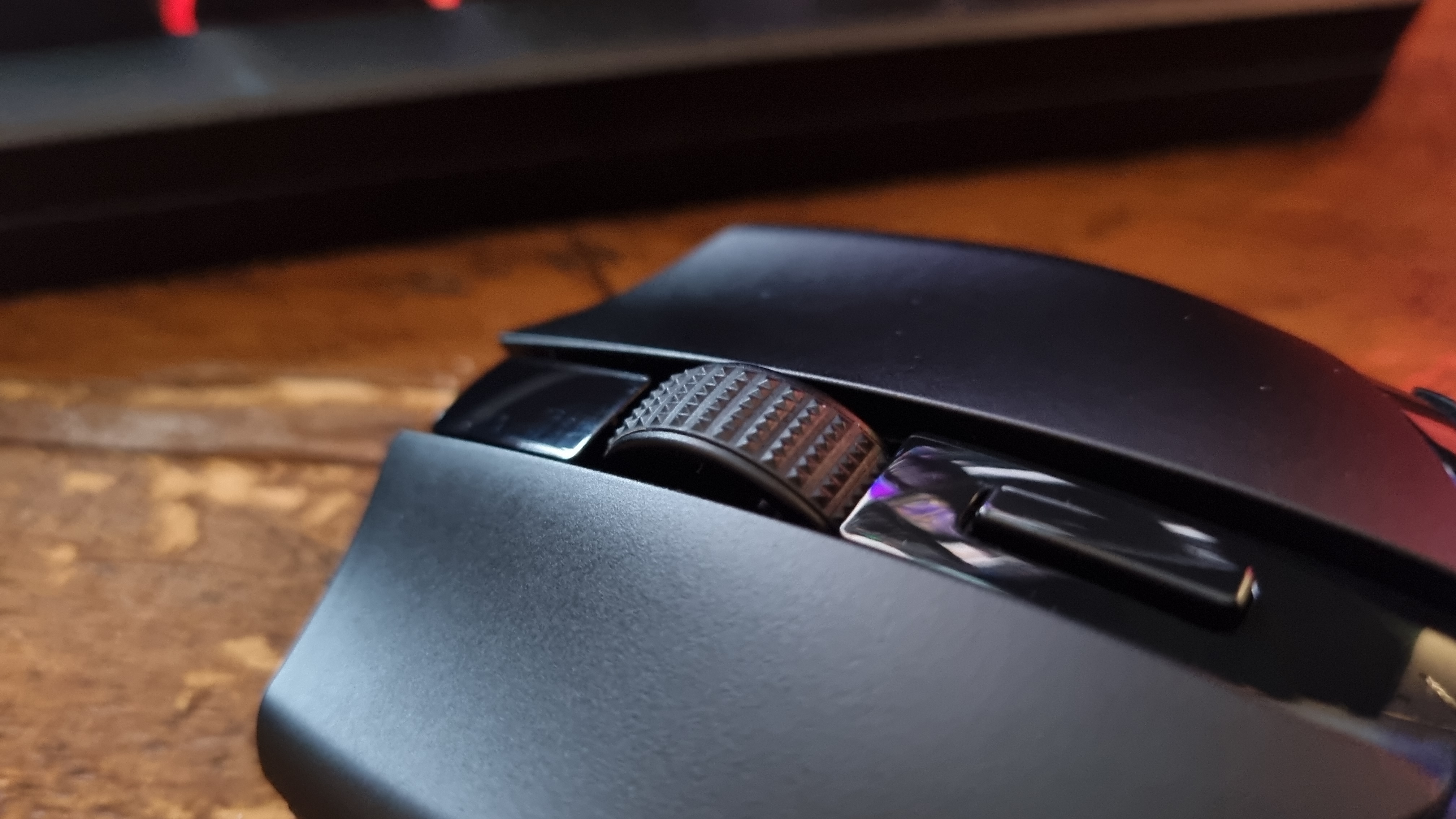 A Razer Cobra HyperSpeed gaming mouse on a wooden desk with its RGB lighting lit in various colours