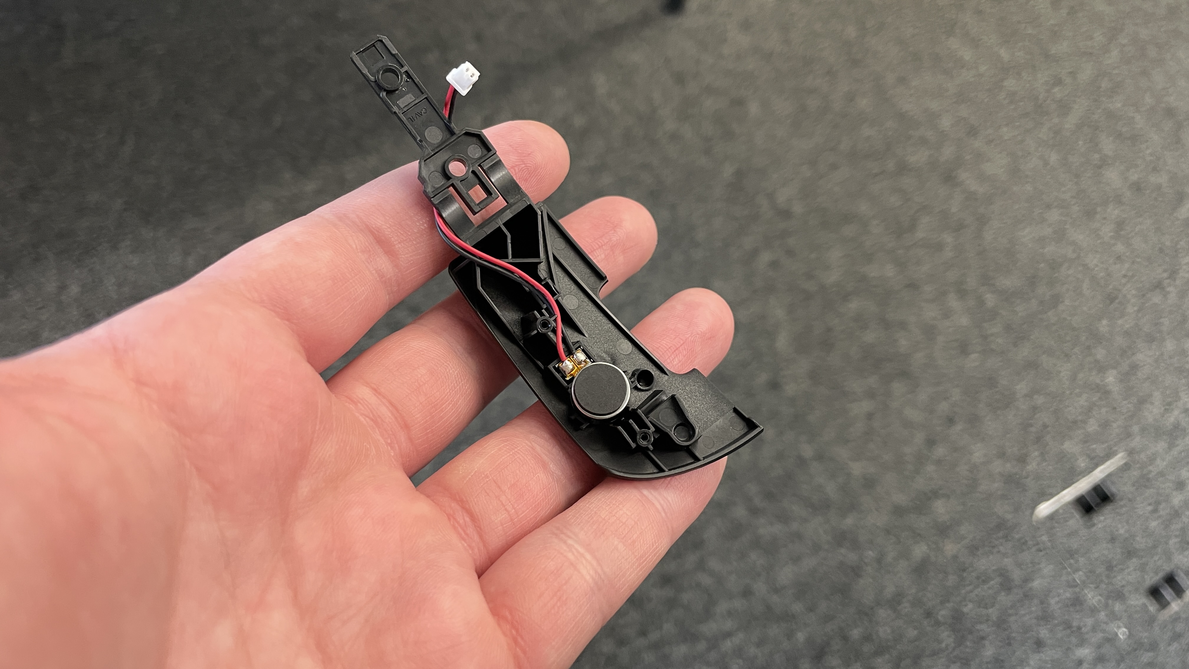 The haptics motor underneath the button plate of a Logitech G Pro X2 Superstrike gaming mouse.