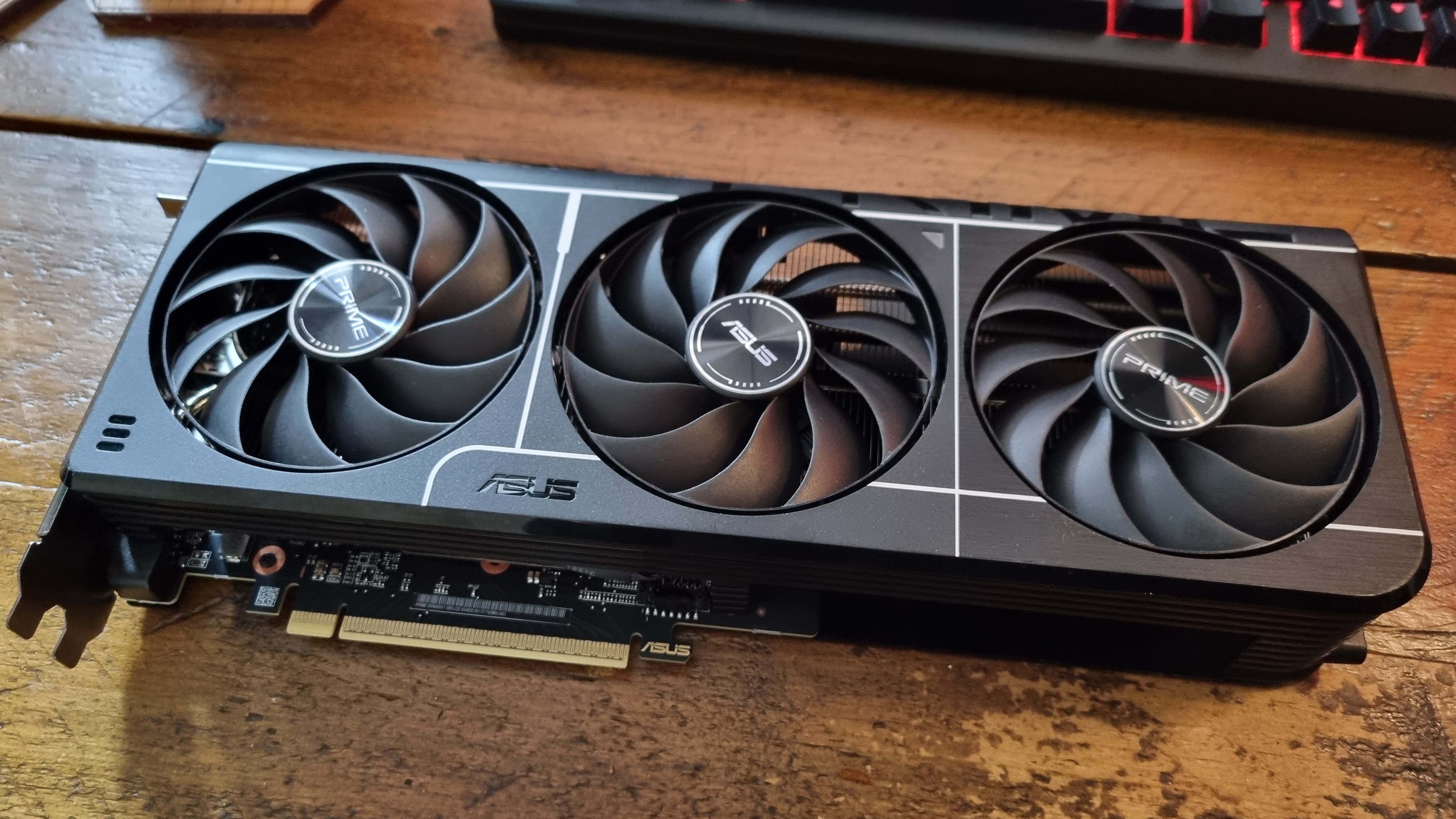 An Asus Prime Radeon RX 9060 XT 8 GB graphics card on a wooden desk