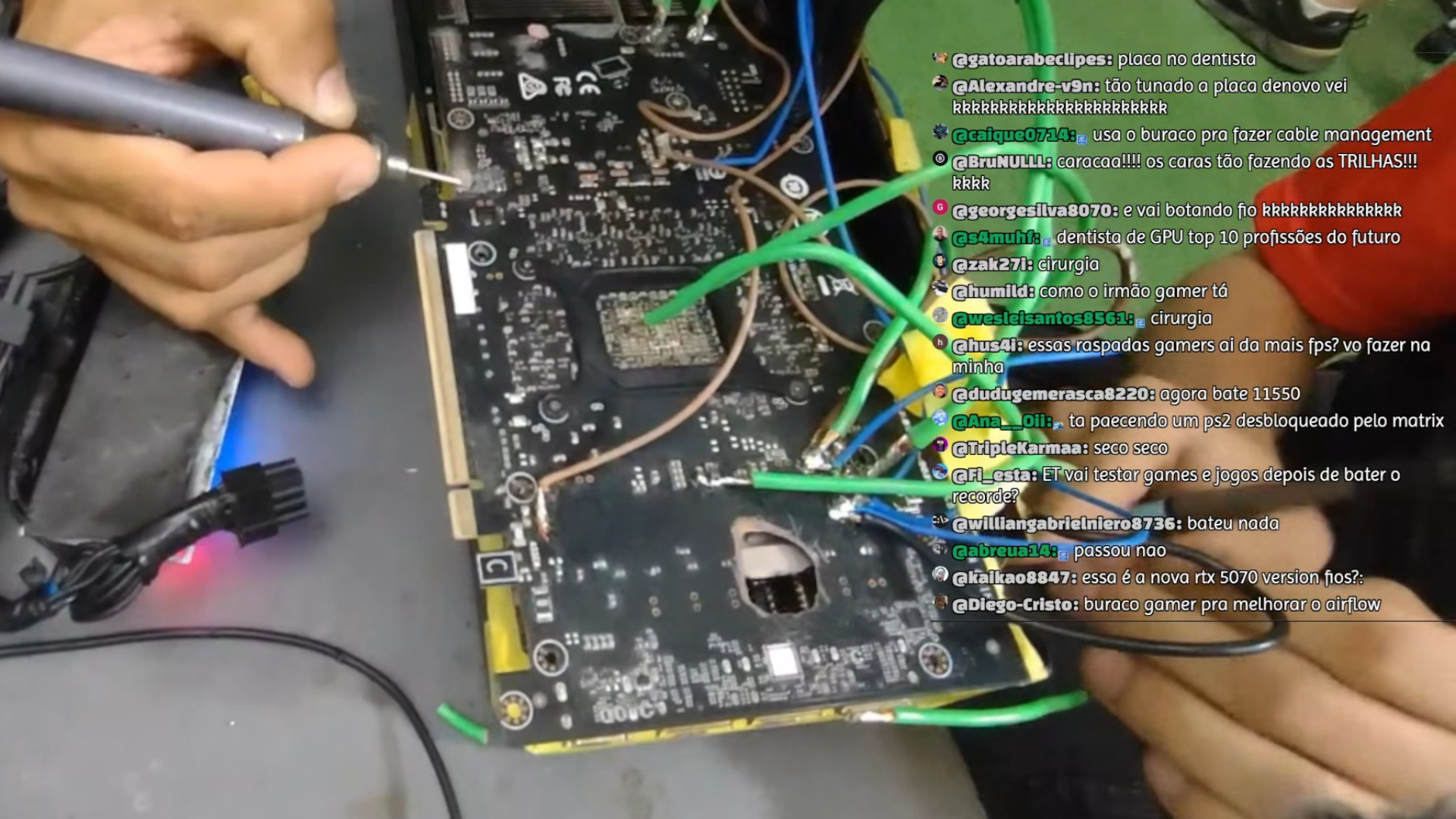 An RTX 5070 Ti with a hole in it being modified on a table, with wires protruding from the circuit board
