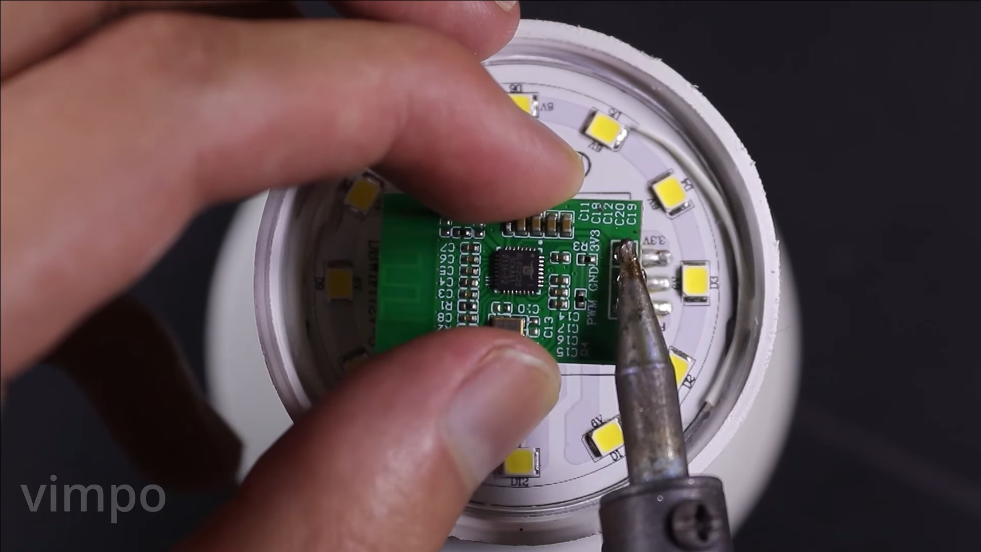 A tiny PCB being removed from a smart bulb to use as a Minecraft server