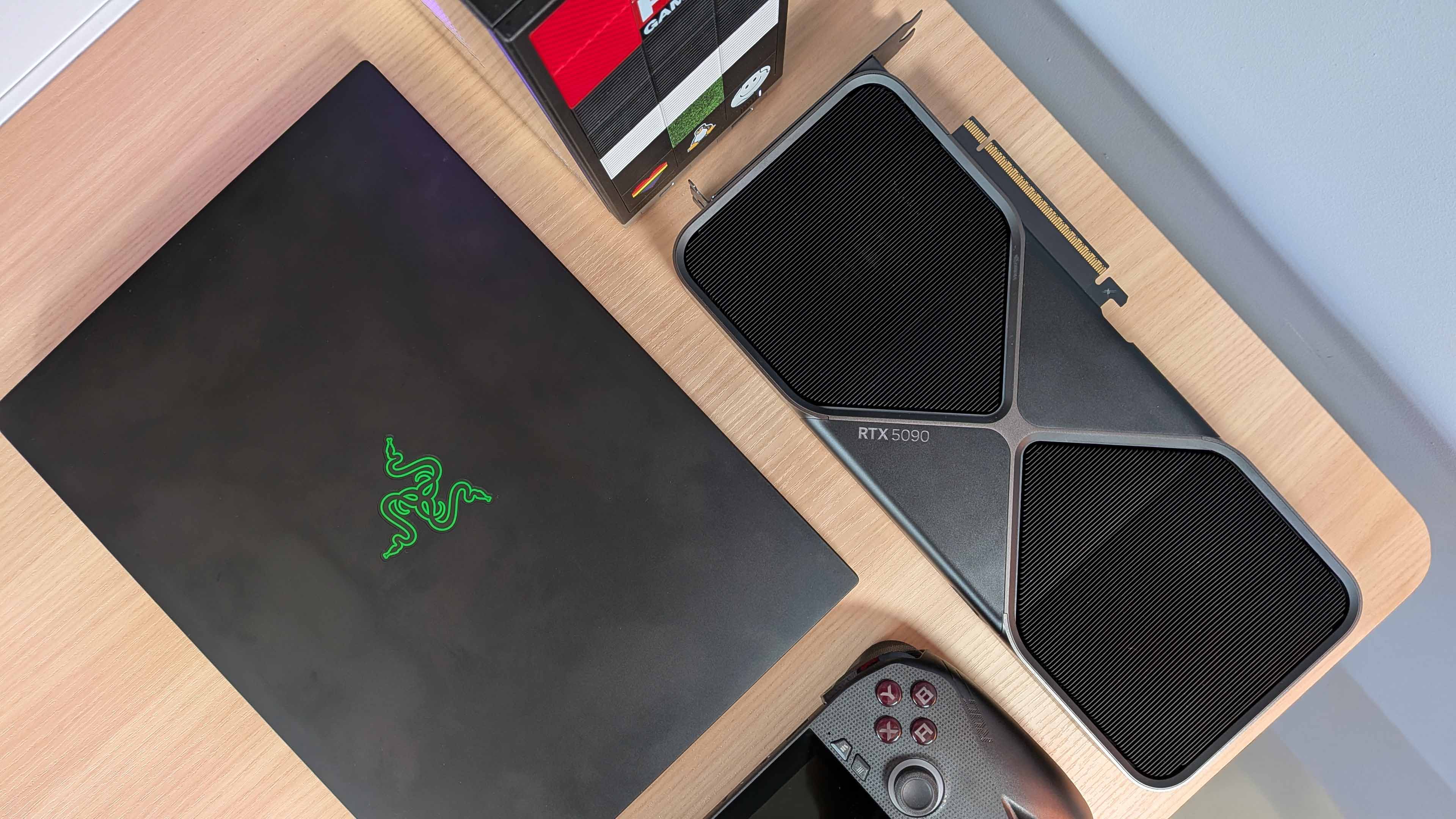 Razer Blade 14, Framework Desktop, RTX 5090 Founders Edition, and Asus ROG Xbox Ally X arranged on a wooden desktop