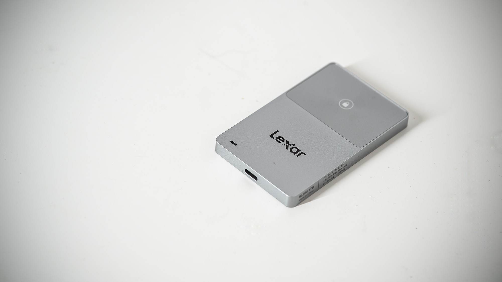 Lexar TouchLock Portable SSD on a white table with a phone.