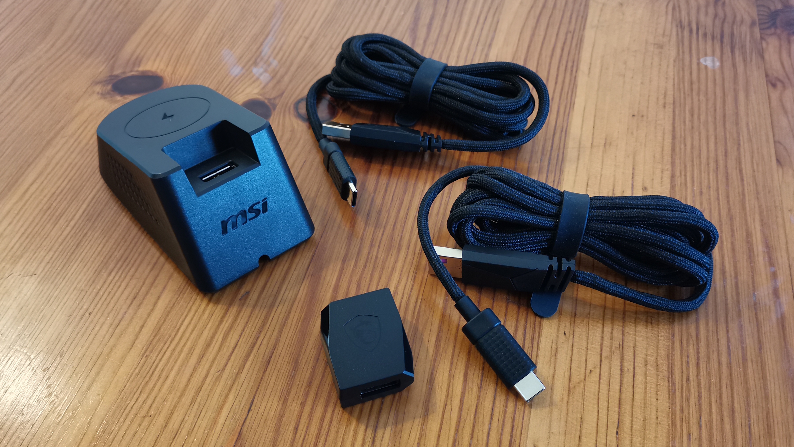 An MSI Versa Pro mouse on a desk with a charging dock and accessories.