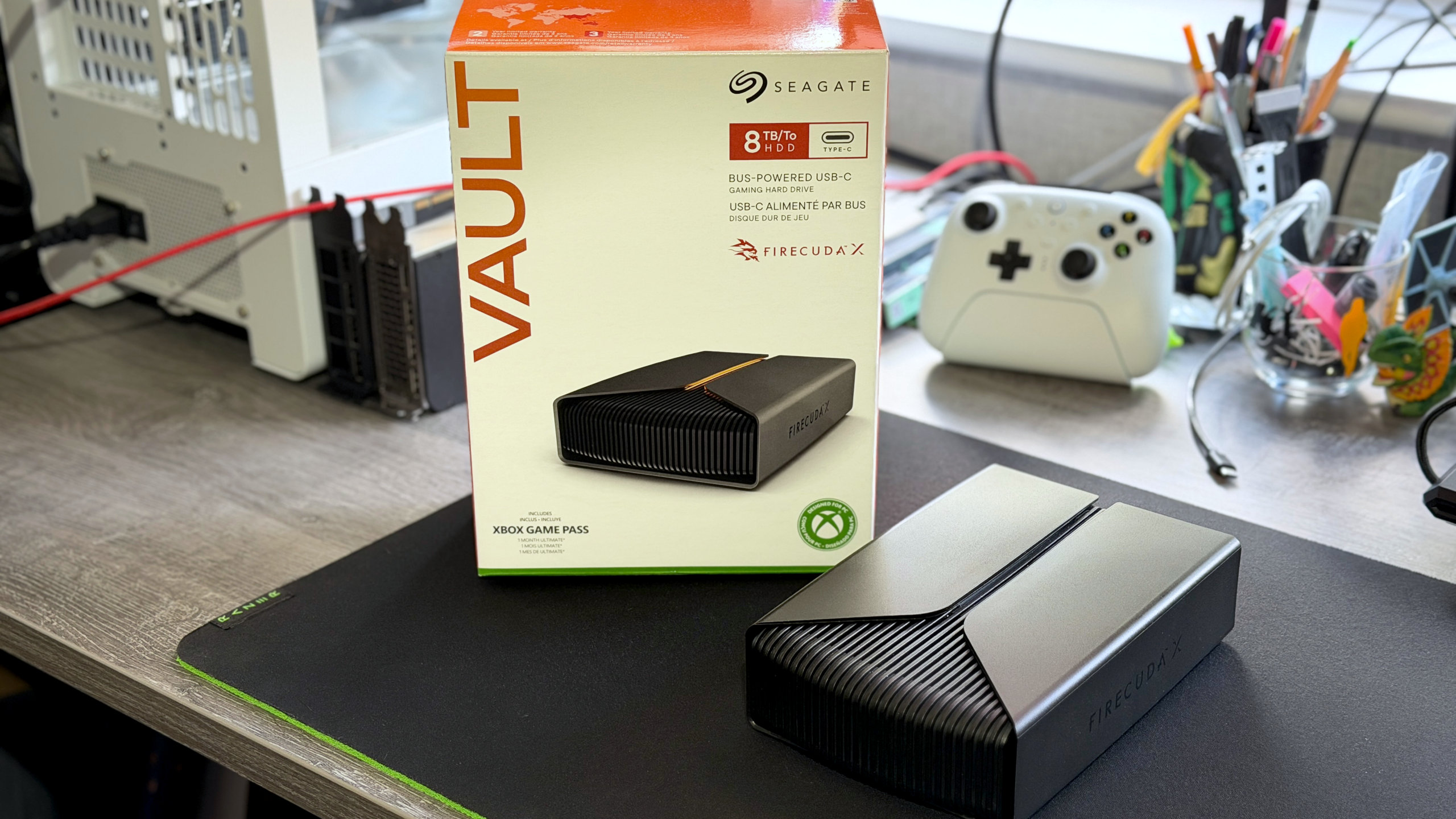 A photo of a Seagate FireCuda X Vault external hdd, resting on a computer desk next to its retail packaging