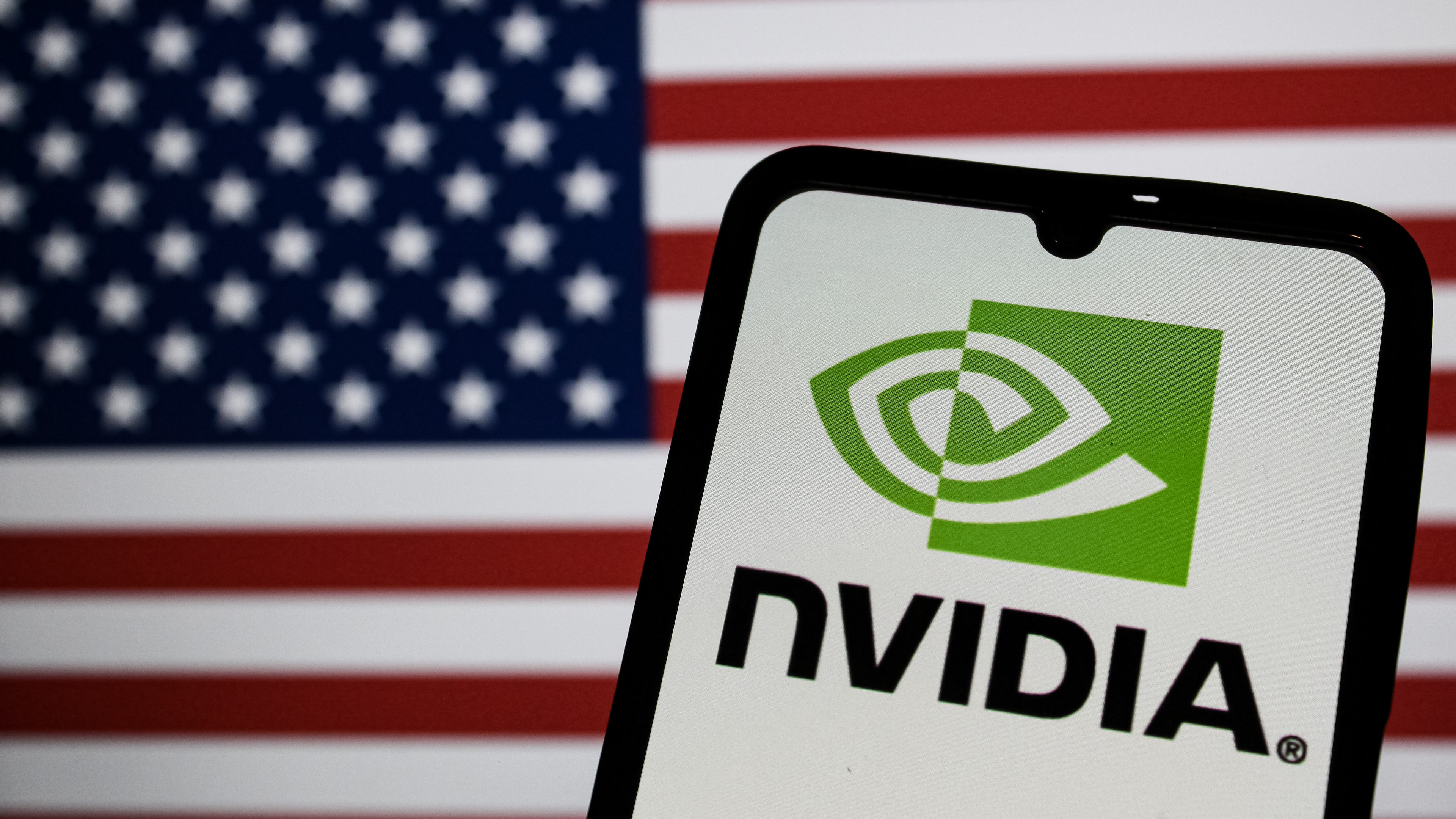 INDONESIA - 2025/03/26: In this photo illustration the Nvidia logo is shown on a mobilephone screen against a computer screen displaying the Flag of America, as the company develops its AI systems. (Photo Illustration by Algi Febri Sugita/SOPA Images/LightRocket via Getty Images)