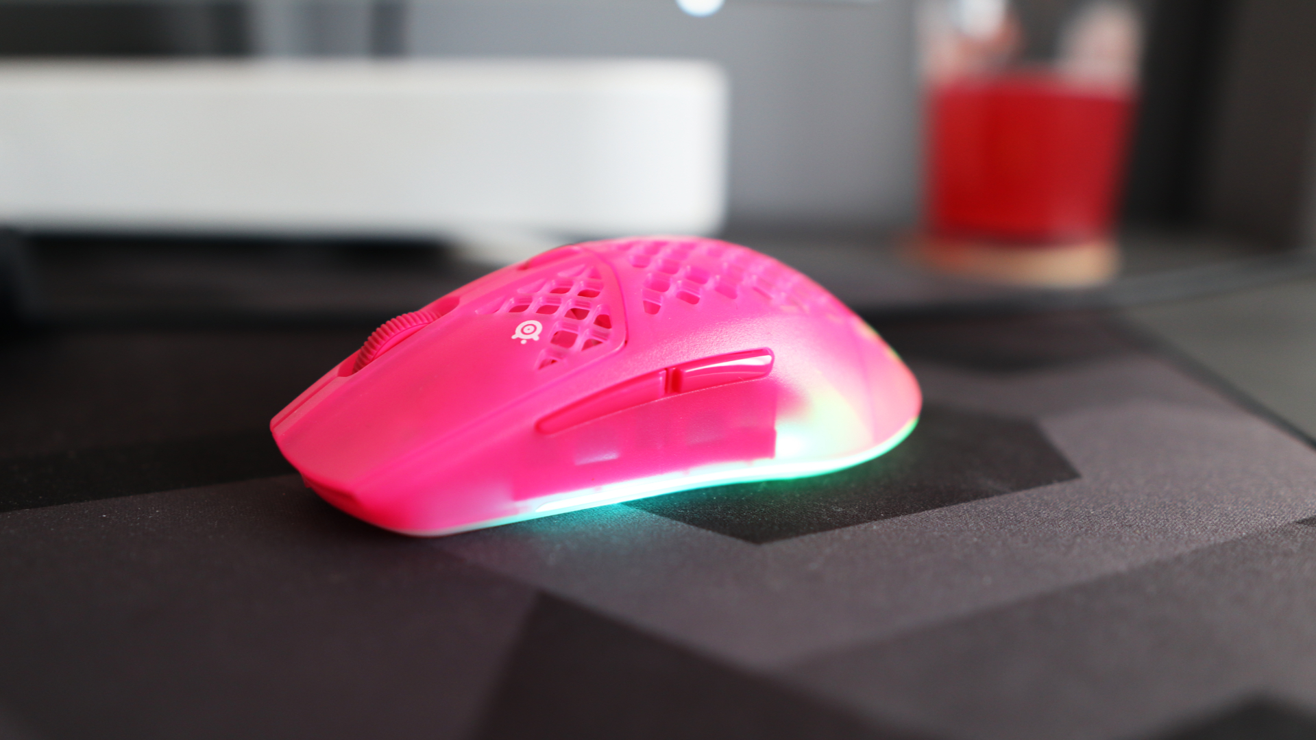 The SteelSeries Aerox 3 Wireless Gen 2 looking excellent in pink on a grey mousepad.