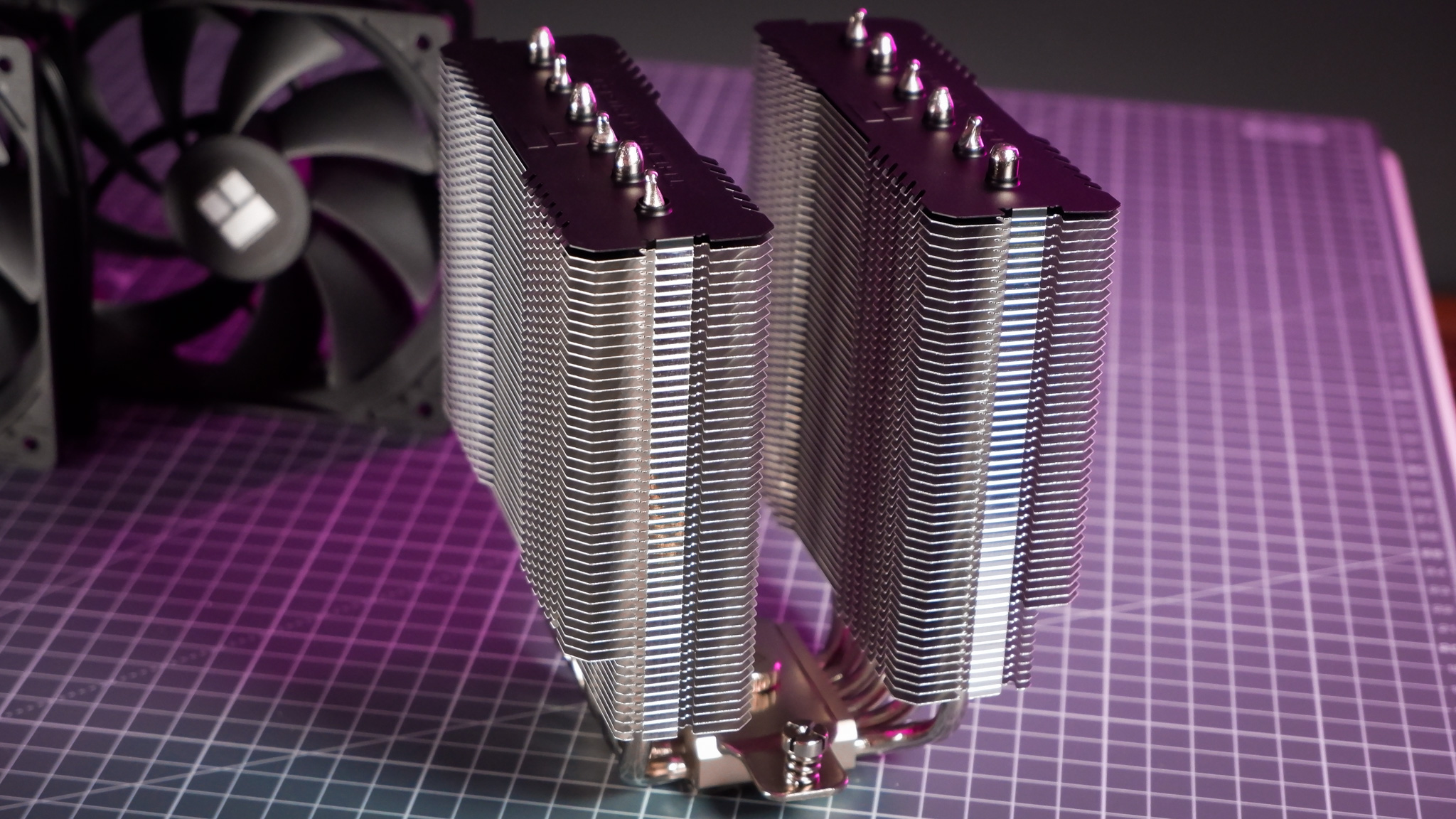 A Thermalright Peerless Assassin 120 SE cooler on a desk with the fans beside it.