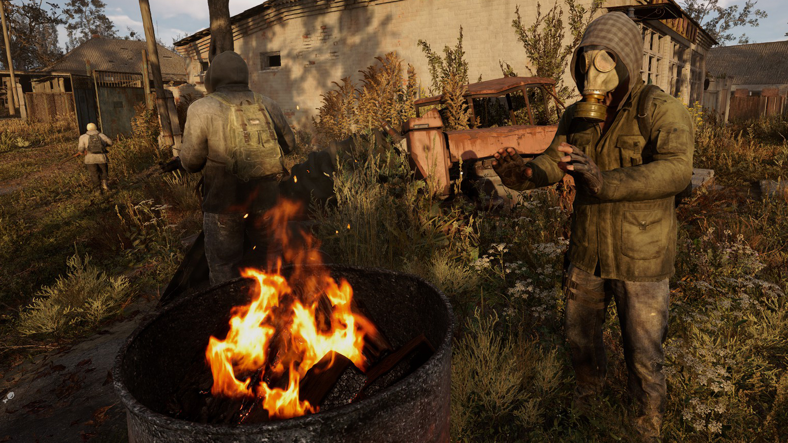 A man in a gasmask warming hands over a fire