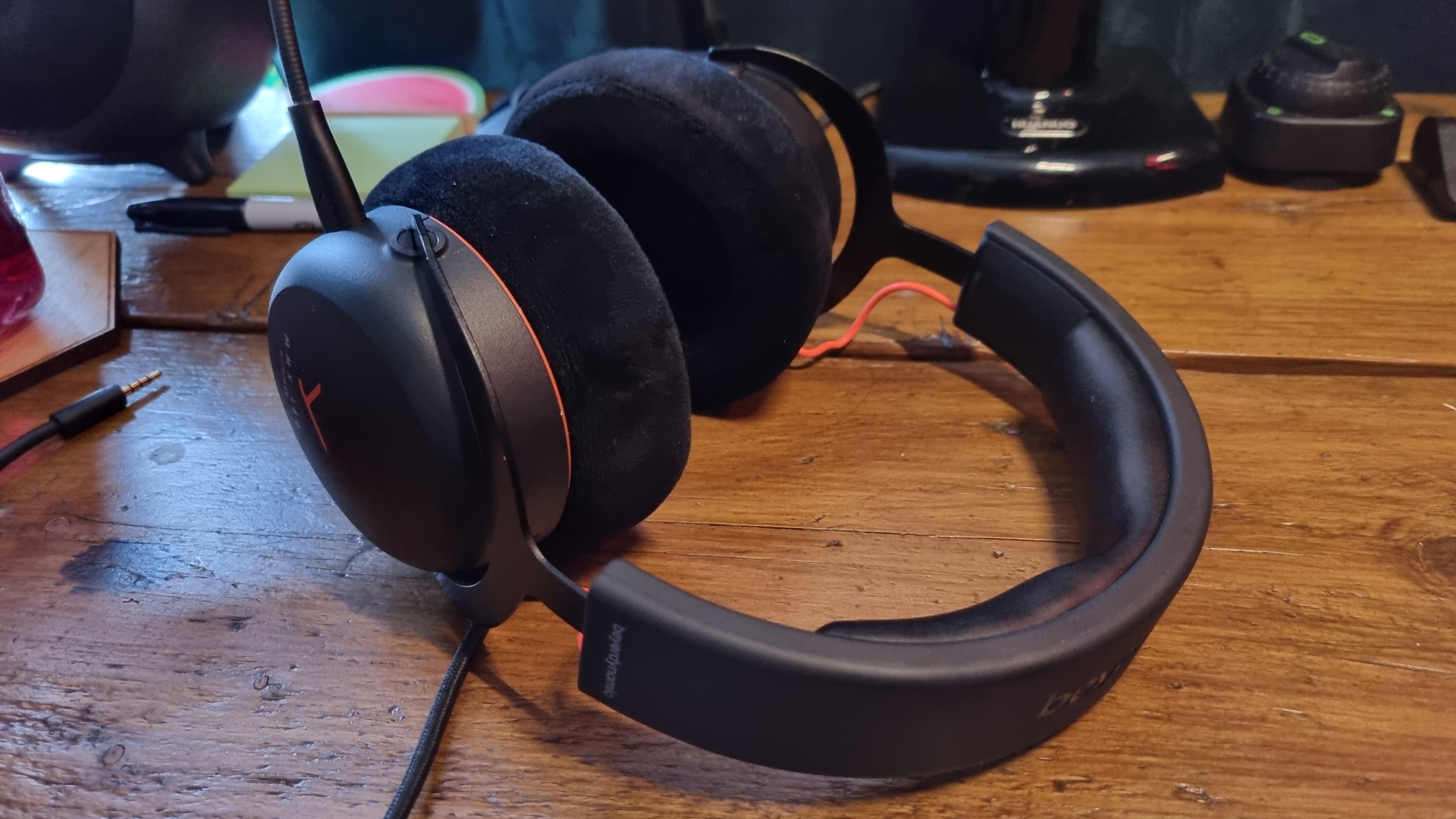 A Beyerdynamic MMX 150 Wireless gaming headset on a wooden desk, headband first