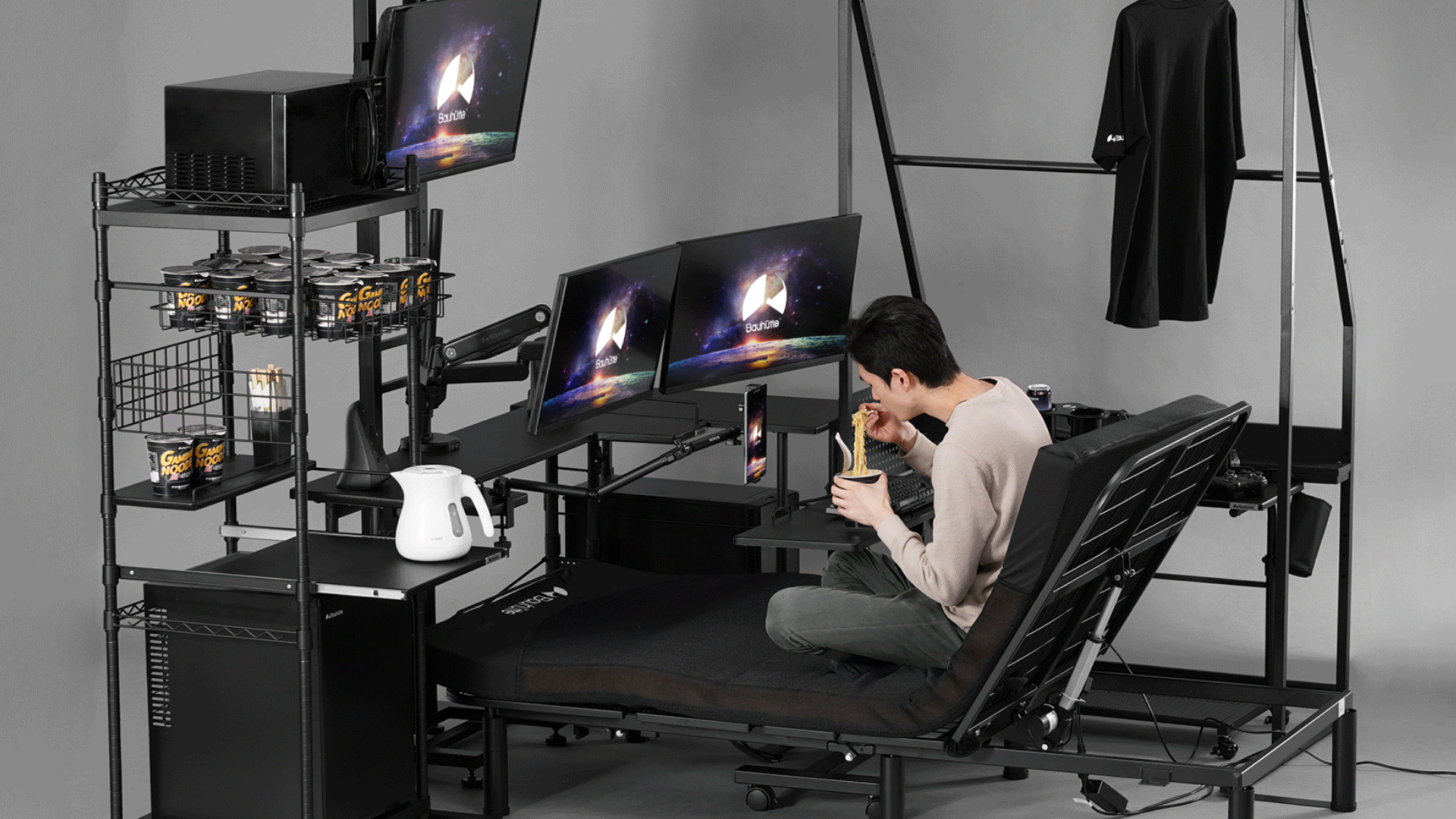 A gamer enjoys a feast of instant noodles while relaxing in his Electric Gaming Bed 2.