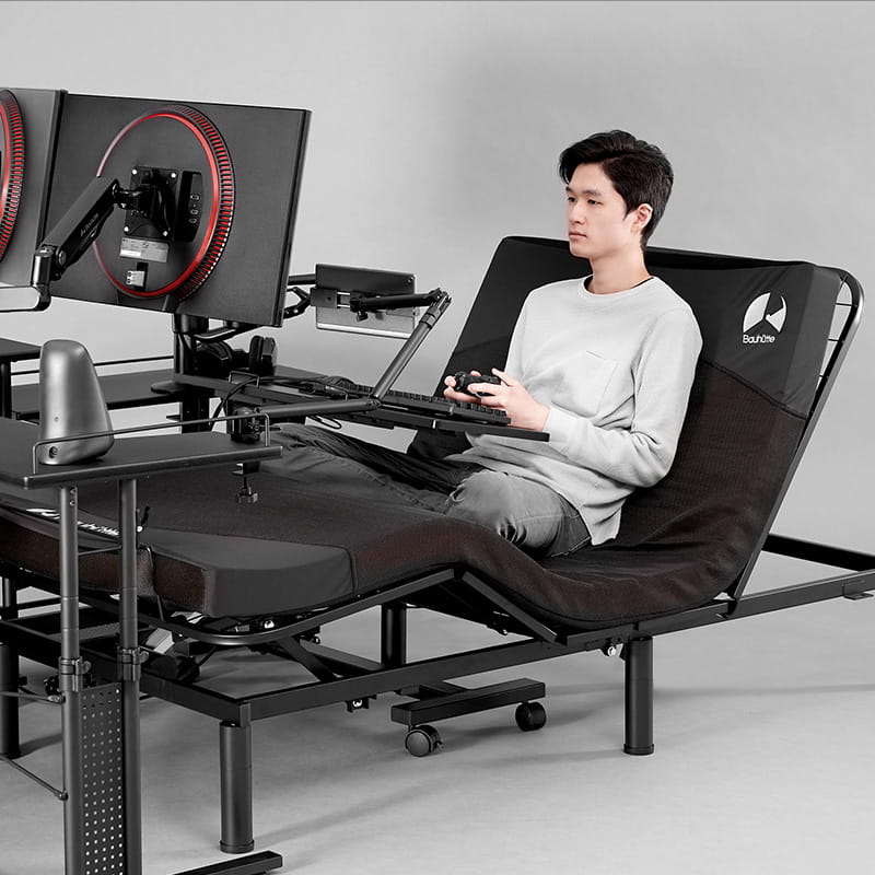 A gamer with his Bauhutte Electric Gaming Bed 2 elevated, for gaming.