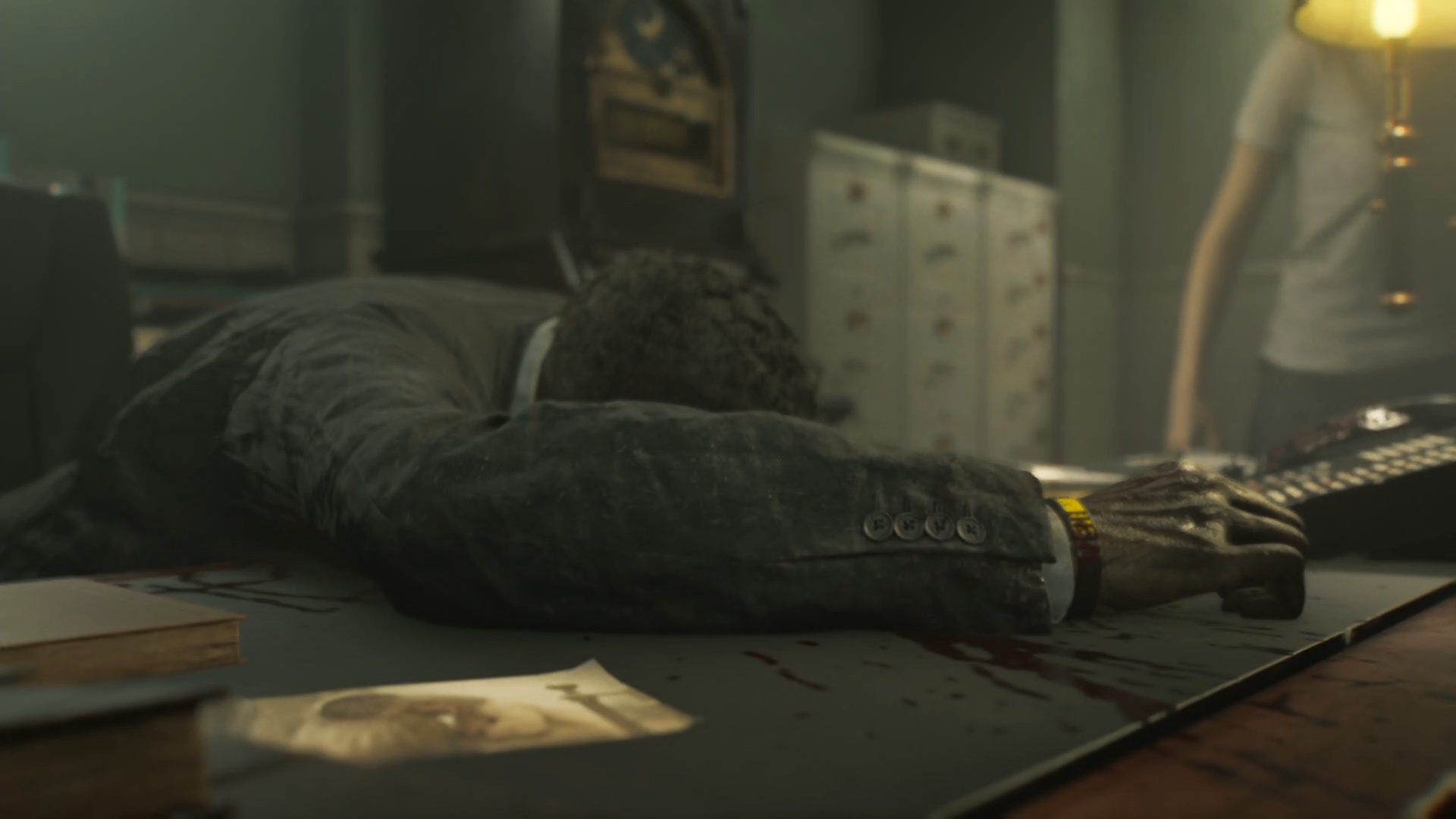 Resident Evil Requiem a corpse holding a gun lies on a desk in the security manager's office