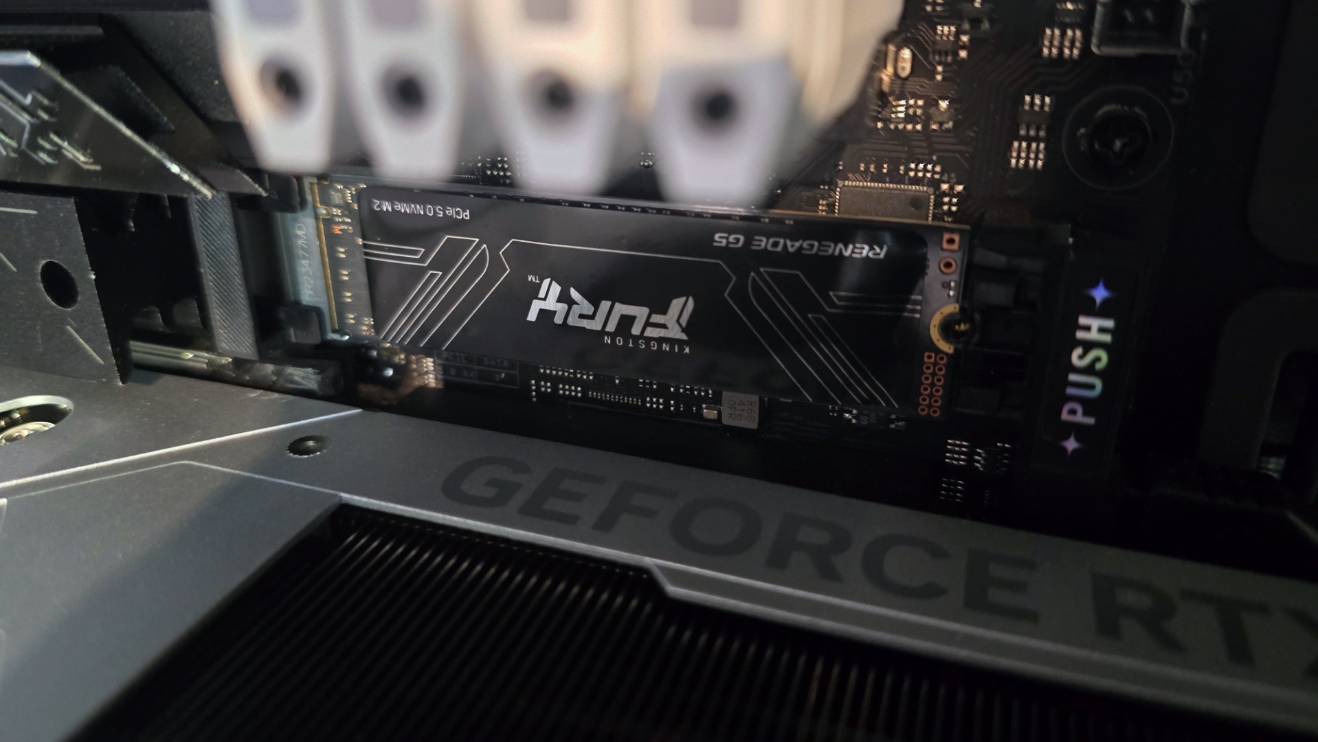 A photo of an 8 TB Kingston Fury Renegade G5 SSD, installed in a gaming PC's main M.2 slot above the graphics card
