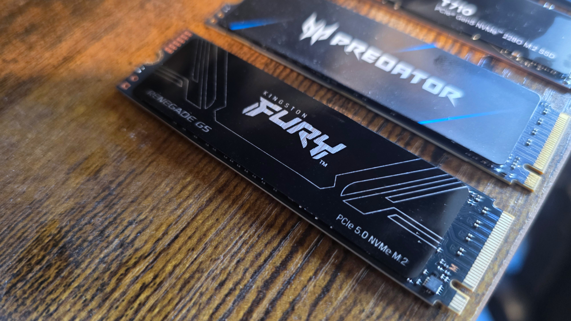A photo of an 8 TB Kingston Fury Renegade G5 SSD, on a desk next to an Acer Predator SSD
