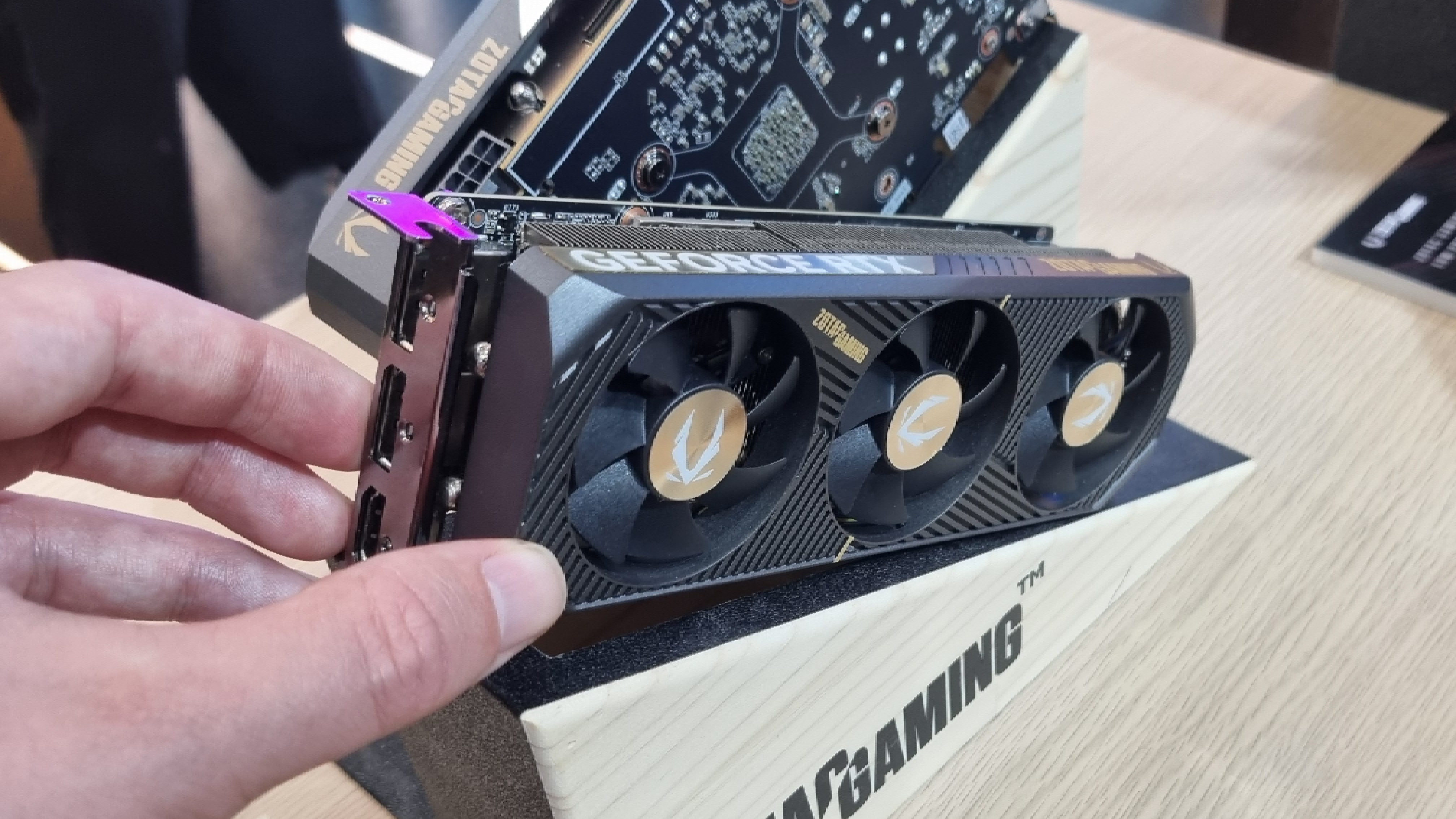 The Zotac Gaming RTX 5060 Low Profile on a display stand, with a hand for scale